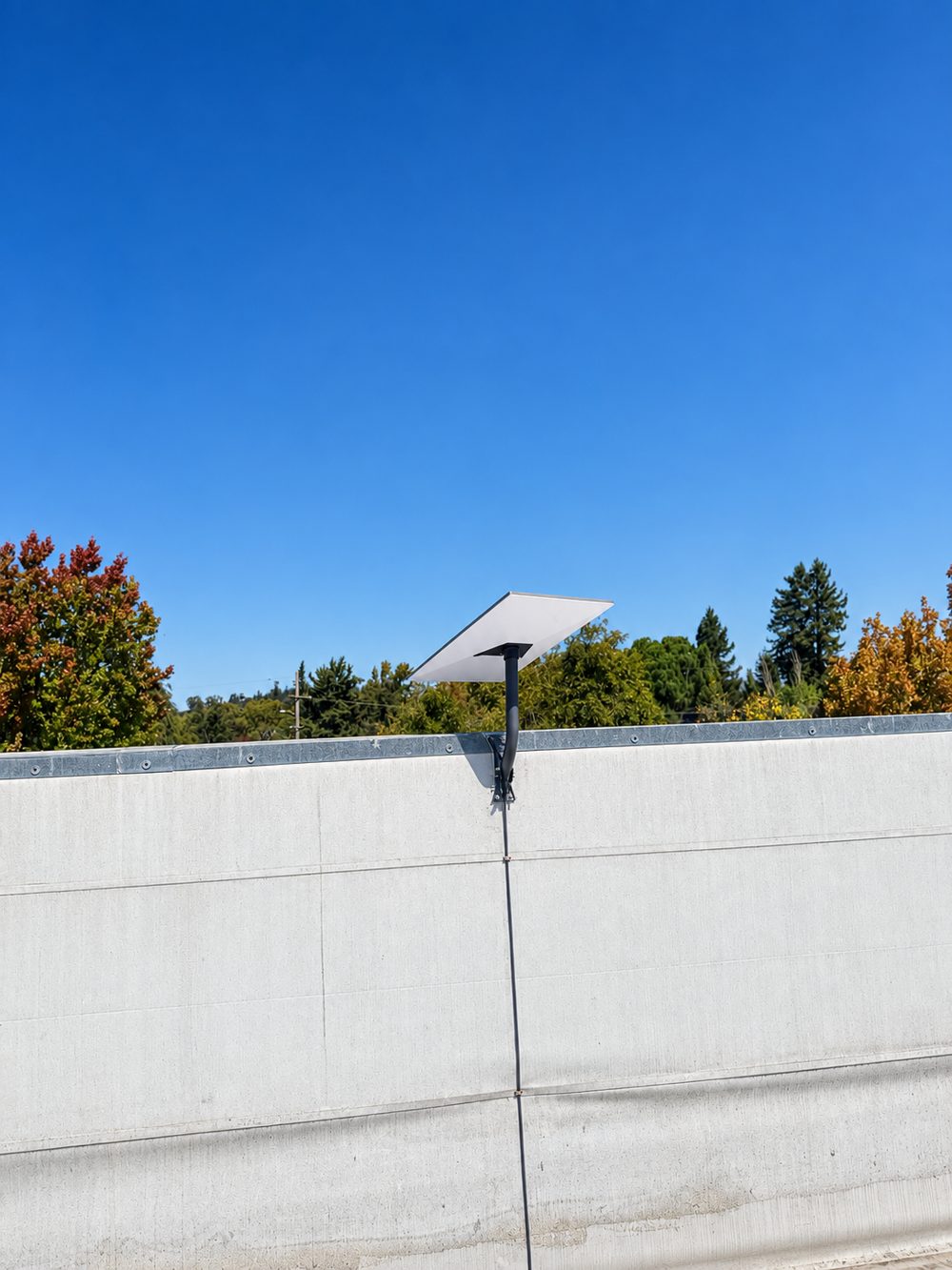 Parapet-mounted Starlink with a clean cable run down the wall